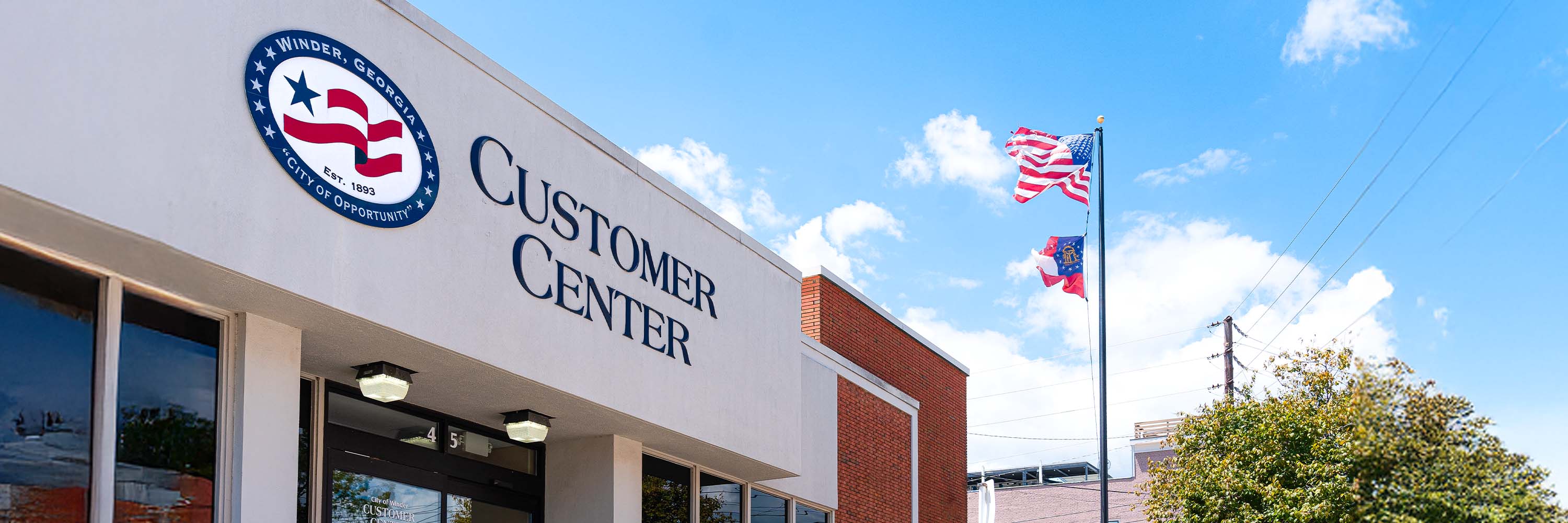 Exterior image of the Customer Center building in downtown Winder, signage and flags waving in background