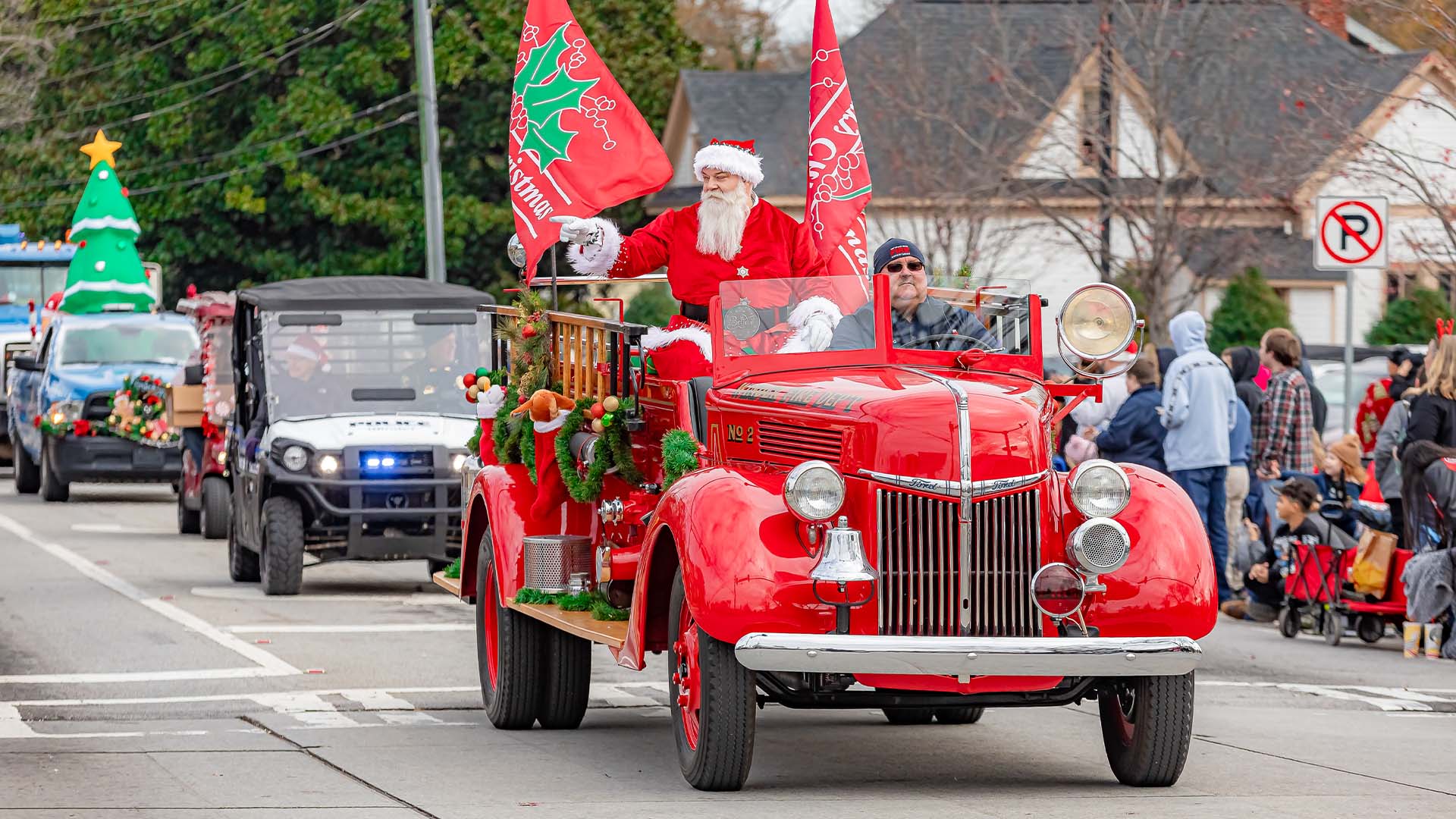Santa Claus riding in a classic red fire truck during the Christmas Parade