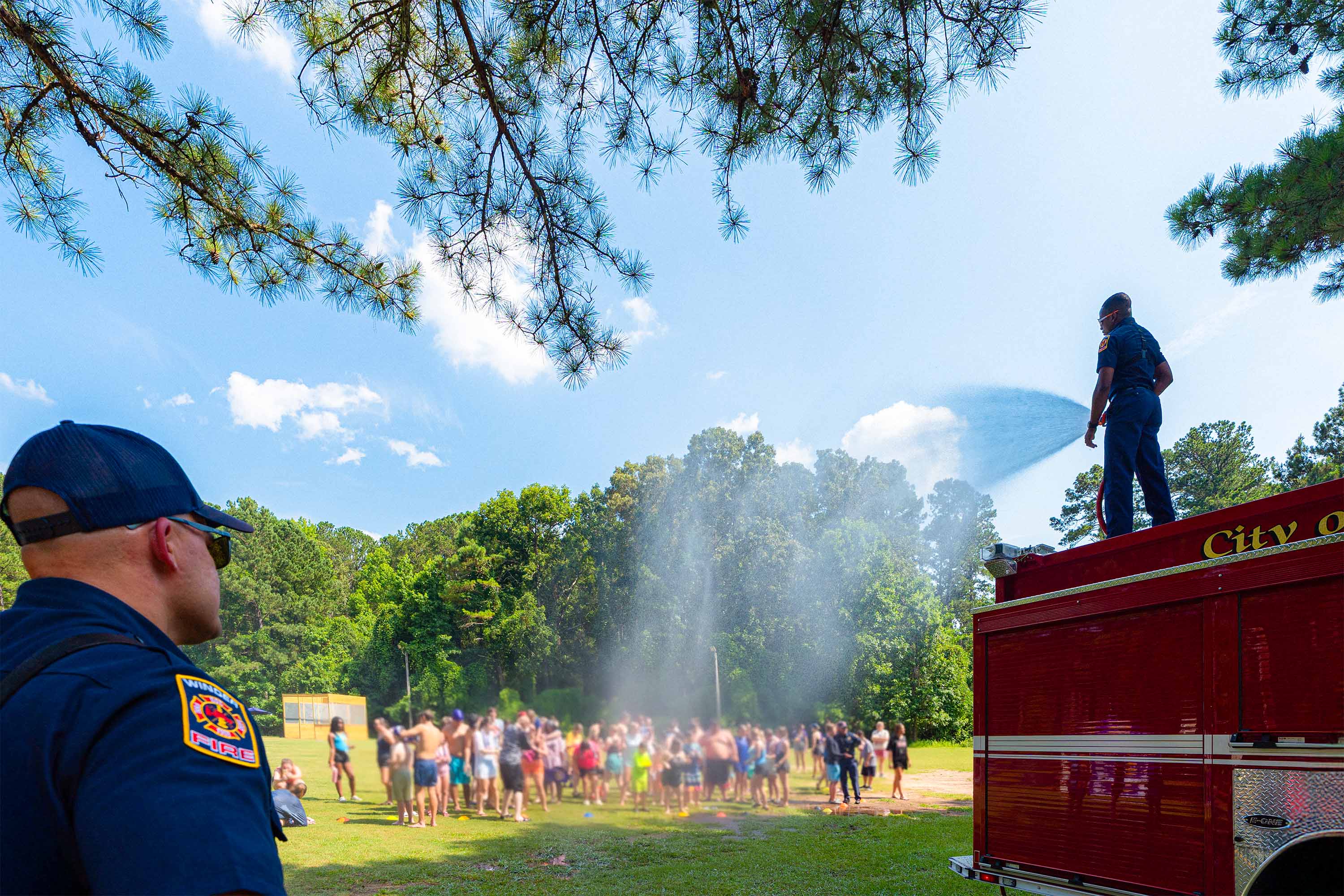 Winder Fire Department firefighters spraying campers at Fort Yargo with a fire hose mist on a hot summer day